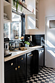 Bright kitchen with black cupboards and chequerboard pattern floor tiles