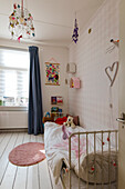 Children's room with metal bed, wall decorations and white floorboards