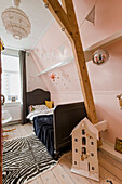 Children's room with black bed, zebra rug, wooden beams and bunting