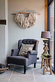 Dark grey wing chair with floor lamp and sheepskin wall hanging