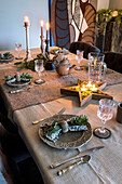 Festlich gedeckter Esstisch mit Kerzen und Tannenzweigen zur Weihnachtszeit