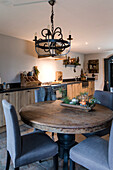 Round wooden table with grey chairs and antique chandelier in kitchen