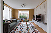 Wohnzimmer mit geometrischer Reliefwand und buntem Teppich