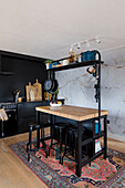 Kücheninsel mit schwarzen Hochstühlen vor Marmorwand