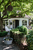 Cosy garden shed with hanging chair and zinc tub under a shady tree