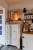 Country kitchen with white vintage cupboard and hanging shelf