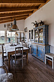 Dining area with rustic wooden table and blue shabby chic display cabinet