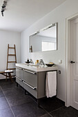 Minimalistisches Badezimmer mit Leiterregal und grauem Waschtisch