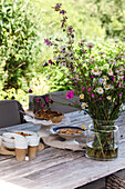 Summer garden table with bouquet of wild flowers and biscuits