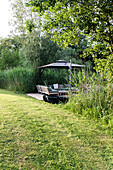 Seating area with sun umbrella and lounge furniture in the garden