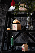 Weihnachtsdekoration mit Madeleine-Keksen, Adventskalender-Boxen, Kerze und Fichtenzweig auf schwarzer Leiter