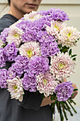 Beautiful bouquet with pale purple carnation and Chrysanthemum flowers in a woman's hands