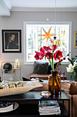 Wohnzimmer mit Amaryllis in Vase, Weihnachtsdeko und Ledercouch
