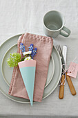 Table decoration with pastel-colored tableware and flower arrangement in paper cone