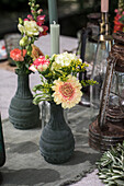 Flower arrangement with zinnias (Zinnia) and carnations (Dianthus) in grey vases next to antique lanterns