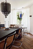 Dining room with black wooden table, rattan chairs and modern pendant light