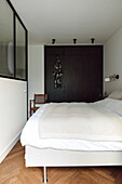 Minimalist bedroom with dark built-in wardrobe and parquet flooring