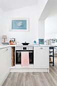 White kitchen with wooden floor and maritime mural