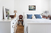 White bedroom with blue accents and wooden floor