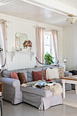 Helles Wohnzimmer mit grauem Sofa, puderfarbenen Vorhängen und Konsole mit Spiegel