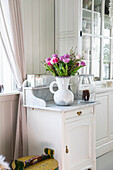 Bouquet of tulips on white sideboard in front of window