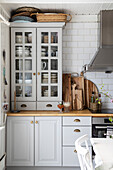 Display cabinet, wooden kitchen boards and extractor bonnet in white country kitchen