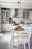 Landhausküche mit weißem Interieur und gedecktem Esstisch