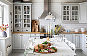 Gedeckter Esstisch in heller Küche im Landhausstil mit weißen Fliesen