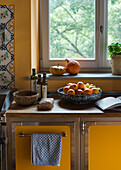 Kitchen with yellow cupboards, fruit bowl on kitchen counter