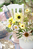 Blumenstrauß mit Sonnenblumen und Echinacea auf Tisch im Garten