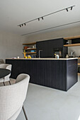 Modern kitchen island with black fronts and integrated appliances, open shelves