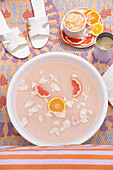 Footbath with petals and orange and grapefruit slices on a colorful carpet