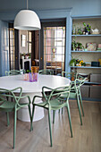 Round dining table with modern green chairs, door with leaded glass windows and built-in shelf