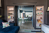 Dark painted living room with view of modern kitchen and built-in shelves