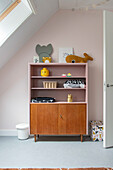 Children's room with wooden shelving and pink-colored wall