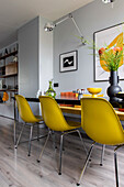 Modern dining area with yellow chairs and wall decoration