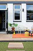 Modern terrace with orange carpet, plastic furniture and plant pot