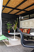 Covered terrace with lounge sofa, white table and plants