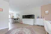 Open-plan living area with kitchen, aquarium and oriental carpet in pastel colours