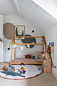 Children's room with house bed and toys under a sloped ceiling