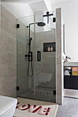 Walk-in shower with rain showerhead and glass walls in the modern bathroom