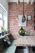 Wooden table with glass vases in front of brick wall, plants on windowsill