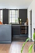 Modern kitchen with dark cupboards, wine rack and wooden floor