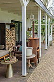 Covered terrace with wood storage, wooden furniture and potted plants