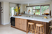 Modern kitchen with wooden island, white worktops and wooden bar stools