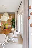 Dining room with oval wooden table, beige chairs and hanging lampshades