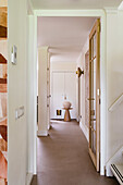 Hallway with light wall colour, glass door and modern wall lamp