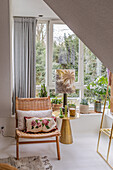 Sitting area with rattan chair and plants in front of large window