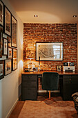 Work area with black desk and office chair in front of brick wall