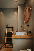 Modern bathroom with round copper mirror and bamboo ladder towel rail